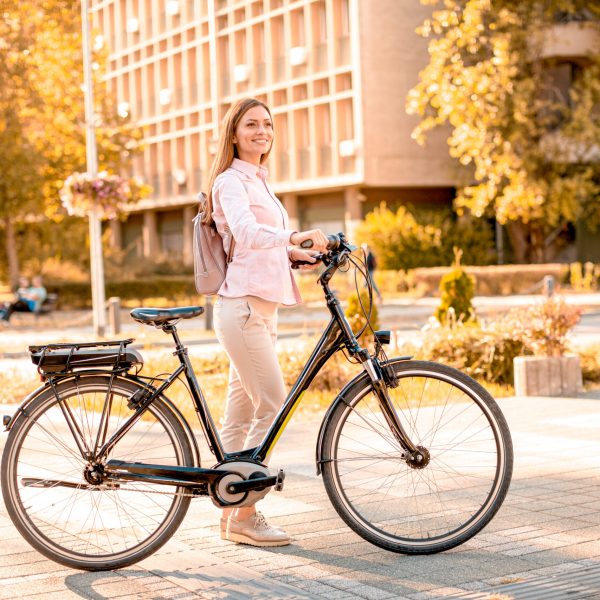 Pretty young woman with modern city electric e-bike clean sustainable urban transportation