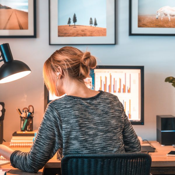 Woman working on computer and digital tablet in her home office during pandemic.