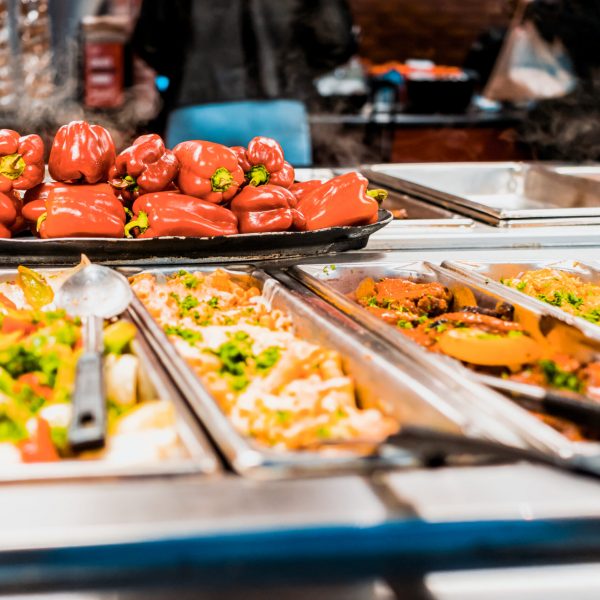 Buffet bar and trays with roasted salad vegetables, red bell peppers and meat dishes